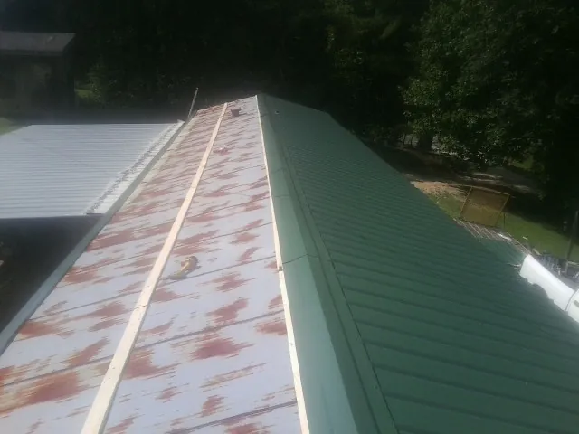 Old rusted panels beside newly installed green metal roofing — Wind Damage Roof Repair by Roofing Brothers in Tolleson