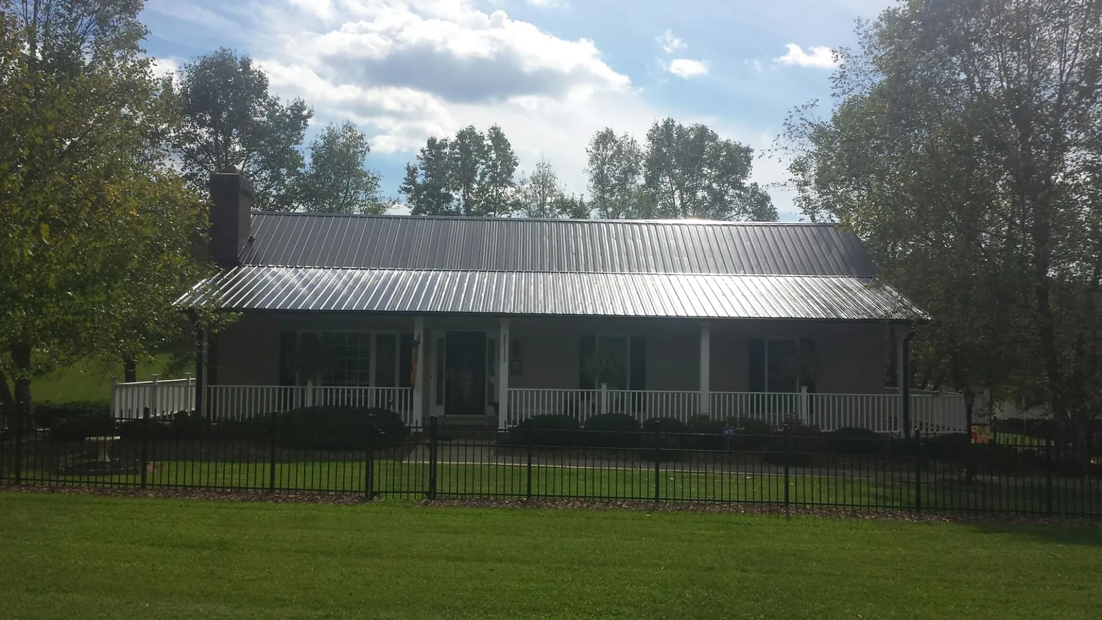 Gray metal roof on a brick ranch with a full width front porch — Gutter Guard Installation work by our crew in Tolleson