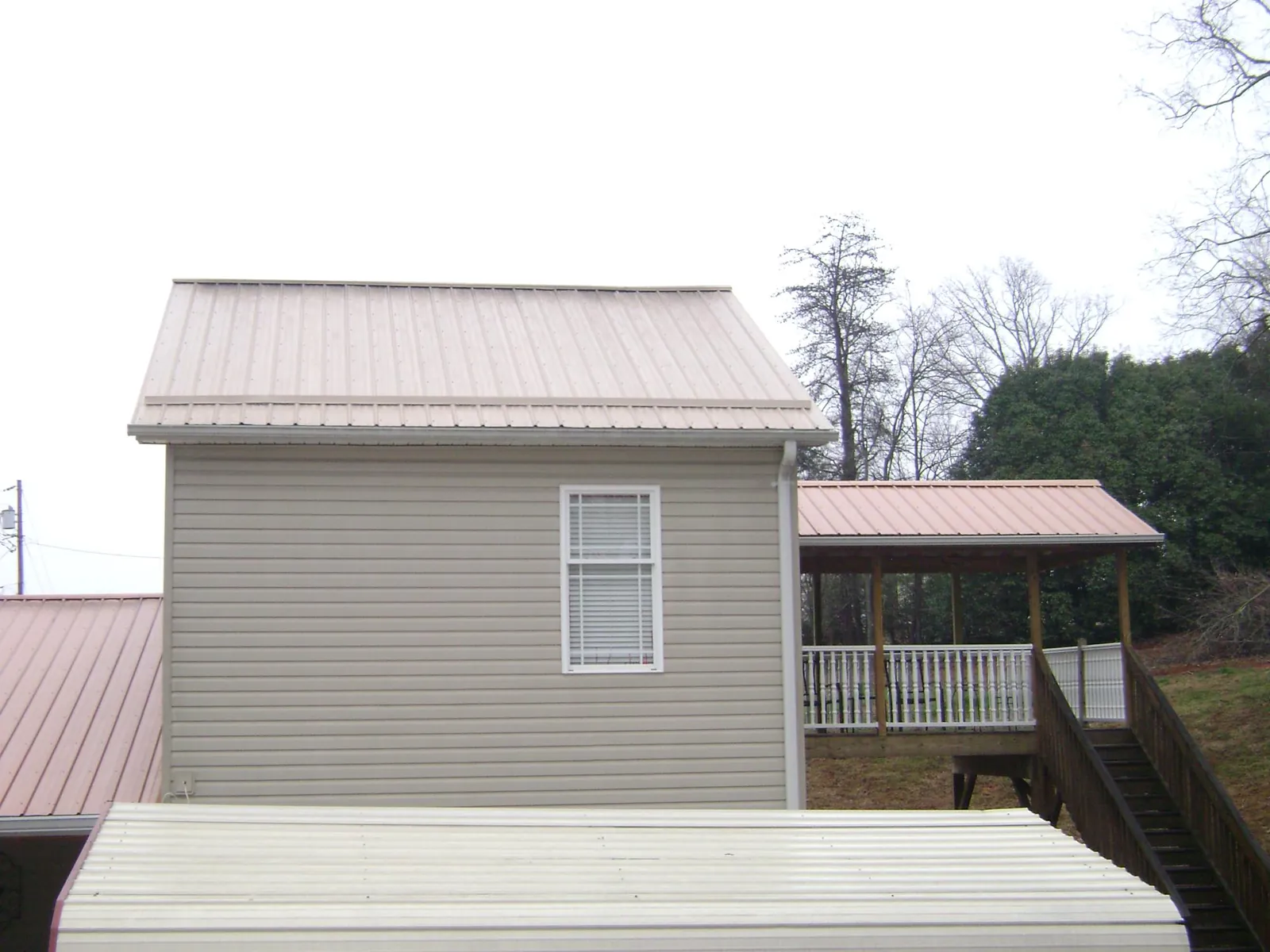 Tan metal roofs on a two story addition and attached porch, from a Roof Replacement job in Tolleson